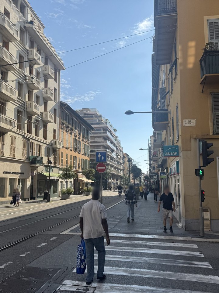 La photo d'origine, prise sur le trottoir de l'avenue ; visages floutés.